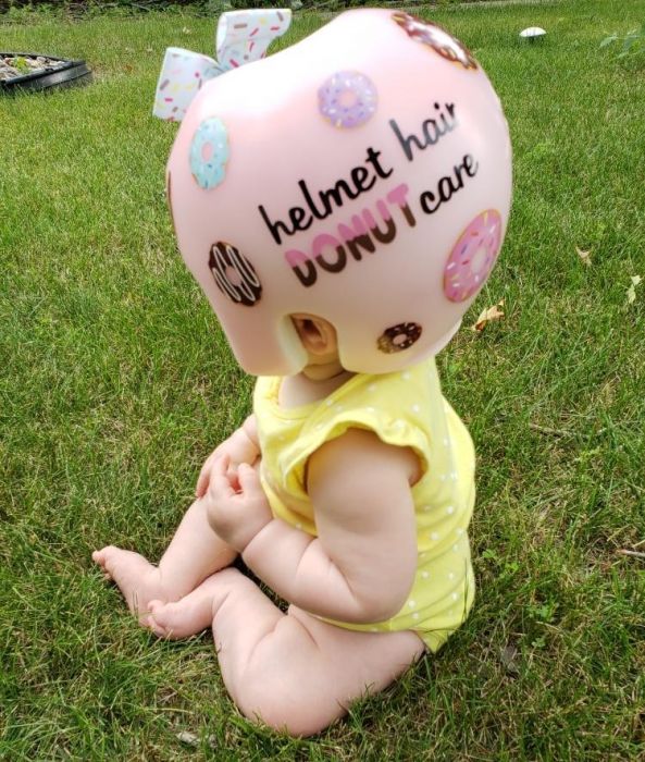 baby in pink cranial remolding orthosis that reads 'helmet hair Donut Care'